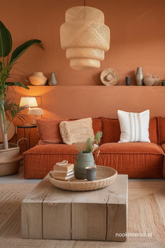 a living room with an orange couch, coffee table and potted plant in the corner