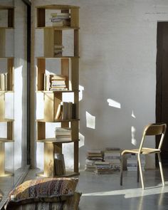 a chair sitting next to a tall wooden book shelf filled with books on top of a hard wood floor