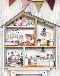 a doll house with furniture and decorations on the top shelf in front of a bunting flag