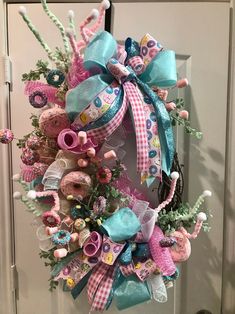 a wreath is hanging on the front door decorated with pink, blue and green items