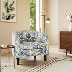 a blue and white chair sitting in a living room next to a table with a vase on it