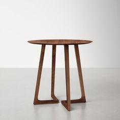 a wooden table with two legs and a round top, on a white floor in an empty room