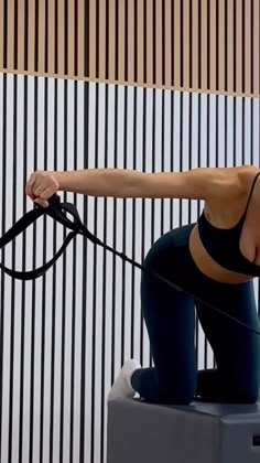 a woman is doing exercises on a stationary exercise machine with her hands behind her back