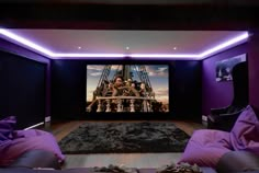 a home theater with purple walls and black carpeted flooring, two couches are facing the screen