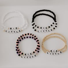 four bracelets with words on them sitting next to each other in gold, black and white