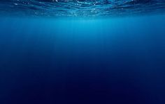 an underwater view of the ocean with blue water and light shining on it's surface