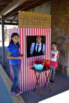 two children standing in front of a ticket booth at an amusement park, with the caption tickets