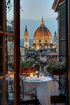 a table with candles on it in front of an open window looking at the city