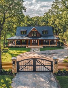 a large house with a metal roof and black gate in the front yard, surrounded by trees