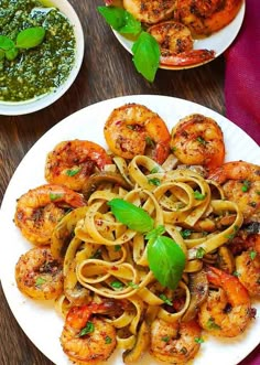 pasta with shrimp and pesto sauce on a white plate next to a bowl of pesto