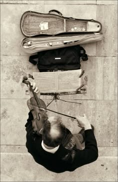 an overhead view of a man playing violin on the ground with other instruments behind him