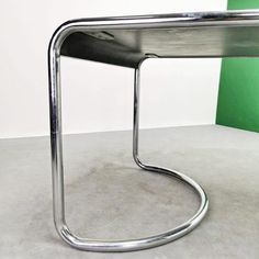 a metal table sitting on top of a cement floor next to a green and white wall