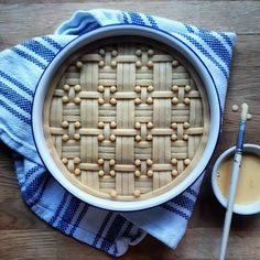 a pie sitting on top of a blue and white towel next to a bowl of sauce