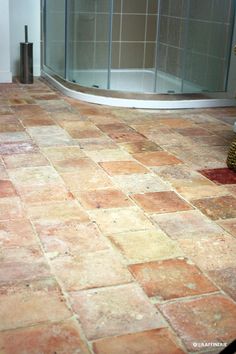 a bathroom with a glass shower door and tiled floor