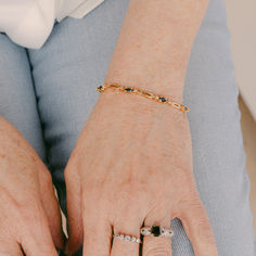 an older woman's hands with rings and bracelets on her wrist, sitting down