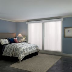 a bed sitting in a bedroom next to a window with white blinds on top of it