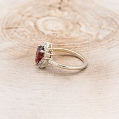 a close up of a ring on top of a piece of wood with a stone