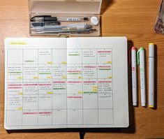 an open planner with markers and pens on a table