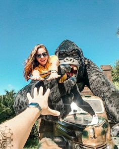 a woman riding on the back of a giant gorilla in front of a man wearing sunglasses