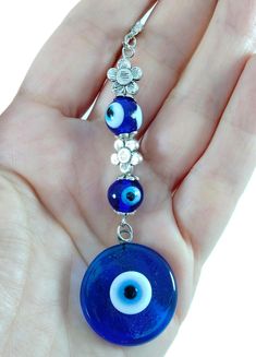 a hand holding a blue evil eye glass bead necklace with silver beads on it