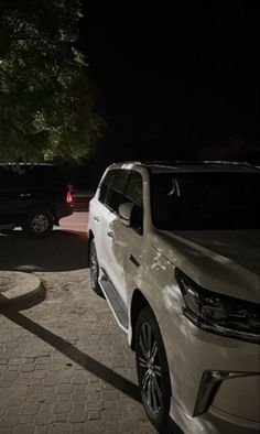 two white cars parked next to each other at night