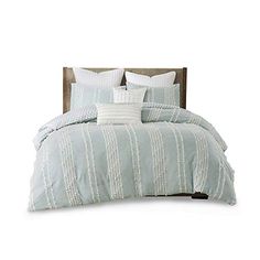 a bed with blue and white striped comforter set on it's headboard