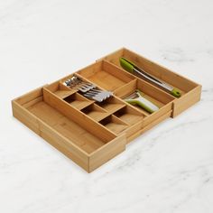 a bamboo tray with utensils in it on a marble countertop next to a knife, fork and spoon