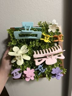 a person holding a flower pot with flowers in it and a hair clip holder attached to the plant