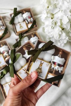 someone is holding some christmas ornaments in their hand and there are white flowers on the table