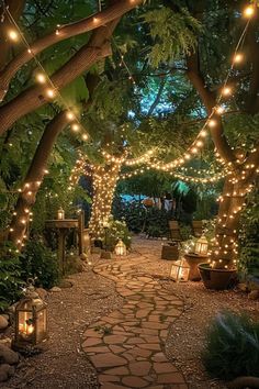 an outdoor walkway with lights strung from the trees and plants on both sides, surrounded by greenery