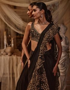 Radiate timeless elegance with this black sari adorned with luxurious ruffles and exquisite golden embroidery. The rich contrast between the deep black fabric and shimmering gold accents creates a stunning visual impact. Drape yourself in this masterpiece to showcase your impeccable style and celebrate the art of traditional craftsmanship with a modern twist. The blouse is crafted from net, while the sari itself is made from georgette. Drape Sari, Black Sari, Golden Embroidery, Black Drapes, Deep Black, Timeless Treasures, Photographic Lighting, Black Fabric, The Deep