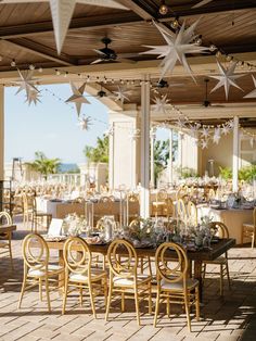 an outdoor dining area with tables and chairs set up for a formal function at the beach