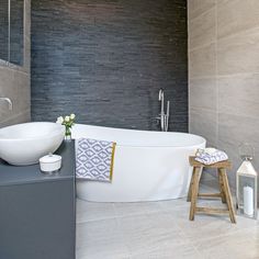 a white bath tub sitting next to a wooden stool