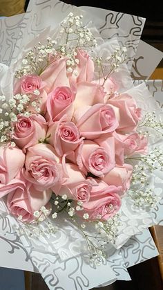 a bouquet of pink roses sitting on top of a piece of paper with baby's breath