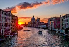 the sun is setting over a canal with boats in it and buildings on both sides