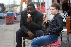 a man and woman sitting on a bench eating ice cream