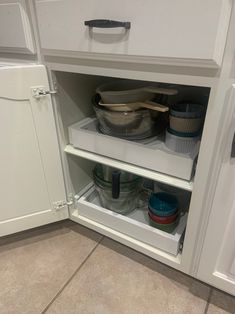 an open cabinet with pots and pans in it