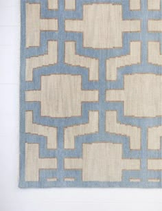 a blue and beige area rug on a white wall