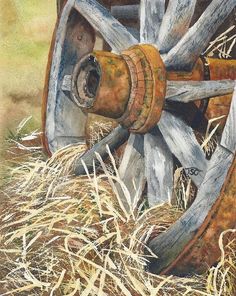 an old wooden wagon wheel sitting on top of dry grass