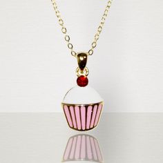 This adorable little cupcake necklace is just as sweet as you little girl. Pink and white enamel with a bright red cherry jewel atop. Outlined in a gold border with a gold chain. What a lovely piece of accessory to compliment any outfit. Suitable for children age 3 and over. Chain length 71/2 in. Sweet Red Jewelry For Valentine's Day, Valentine's Day Sweet Gold Jewelry, Sweet Gold Jewelry For Valentine's Day, Sweet White Jewelry For Valentine's Day, Cute White Charm Necklace For Birthday Gift, Cute Enamel Necklaces For Gifts, Sweet Gold Necklace For Gift, Sweet Gold Necklace As Gift, Sweet Gold Necklace Perfect For Gift