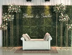 a white couch sitting in front of a wall with flowers and greenery on it