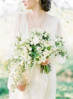 a woman holding a bouquet of white flowers