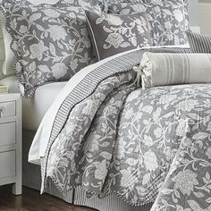 a bed covered in gray and white comforters