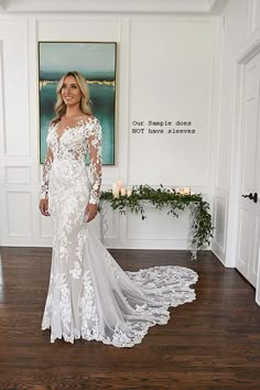 a woman in a white wedding dress standing on a wooden floor next to a painting