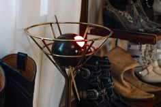 a candle that is sitting in a glass vase on a stand next to shoes and boots