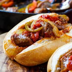 some very tasty looking hot dogs in buns on a wooden table with other food items