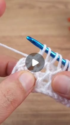 someone is crocheting the end of a piece of white yarn with a blue needle