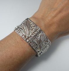 Here is an exceptional Art Nouveau completely handmade silver filigree bracelet circa 1890. The workmanship here is reminiscent of 18th century filigree in the quality and intricacy of this amazing piece. Each panel is entirely made by hand with silver wire twisted and wound into a fern and frond design each bouquet tied with a feminine bow. Amazingly each panel is not flat but the silver lace design is raised in relief with the central fern frond sitting higher to the rest of the panel. When th Victorian Jewelry With Decorative Band For Formal Occasions, Elegant Ceremonial Engraved Cuff Bracelet, Elegant Engraved Ceremonial Cuff Bracelet, Victorian Formal Jewelry With Decorative Band, Elegant Engraved Cuff Bracelet For Ceremonial Occasions, Wedding Filigree Bangle Bracelets, Luxury Silver Engraved Filigree Ring, Luxury Engraved Silver Filigree Ring, Victorian Cuff Bracelet With Intricate Design For Ceremonial