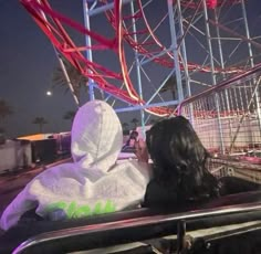 two people sitting in the back of a car at an amusement park