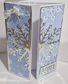 two folded cards with snowflakes on them, one is blue and the other is white